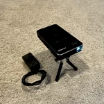 Akaso WT50 Dlp Smart Wireless Mini Projector Black With Tripod And Power Adapter. Fixed Price $205.00.